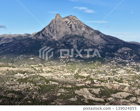 Majestic Rocky Height Emerging Above Plains, Vast Rocky Peak Soaring High Above Gentle Valley Landscape Below Majestic Rocky Height Emerging Above Plains, Vast Rocky Peak Soaring High Above Gentle Valley Landscape Below 139024855