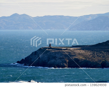 Remote Lighthouse Standing On Rough Shoreline With Ominous Clouds Overhead And Turbulent Waters Remote Lighthouse Standing On Rough Shoreline With Ominous Clouds Overhead And Turbulent Waters 139024930