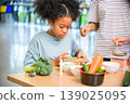 Child focusing on vegetable preparation in classroom nutrition education project for health learning 139025095