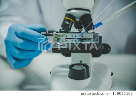 Close up scientist using pipette on microscope slide in laboratory experiment for biology chemistry and medical study 139025102