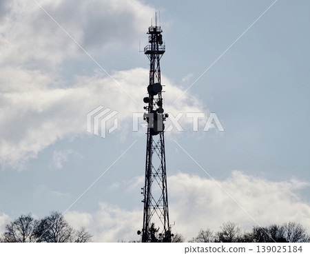 Tall Tower Topped With Antennas Amid Clouds. Silhouetted Tower Against Stormy Sky With Signals Emanating Tall Tower Topped With Antennas Amid Clouds. Silhouetted Tower Against Stormy Sky With Signals Emanating 139025184