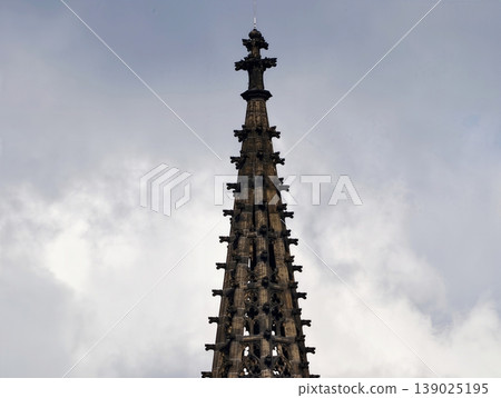 Spired Gothic Architecture Details. Elaborate Stone Pinnacle Featuring Layered Spire And Clouded Sky Spired Gothic Architecture Details. Elaborate Stone Pinnacle Featuring Layered Spire And Clouded Sky 139025195