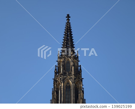 Imposing Gothic Spire Rises Sharply From Cathedral Silhouette Beneath Vast Blue Atmosphere 139025199