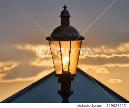 Sunset Illumination With Retro Charm. Oldfashioned Lantern Illuminates Rooftop With Inviting Sunset Glow Sunset Illumination With Retro Charm. Oldfashioned Lantern Illuminates Rooftop With Inviting Sunset Glow 139025515