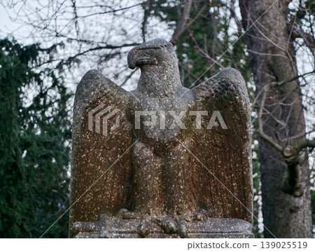 Mosscovered Eagle In Woods. Serene Mossy Forest Surrounds Worn Eagle Statue With Dark Shadows 139025519