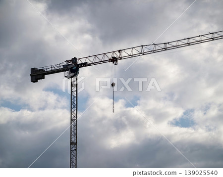 Cranes Under Clouds. Cinematic Scene Showcasing Tower Crane In Dramatic Industrial Urban Setting Cranes Under Clouds. Cinematic Scene Showcasing Tower Crane In Dramatic Industrial Urban Setting 139025540