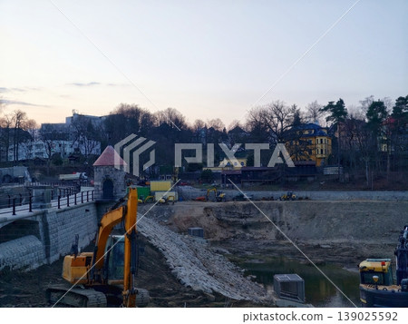 Construction Zone During Evening With Heavy Machinery Creating Embankments And Muddy Paths 139025592