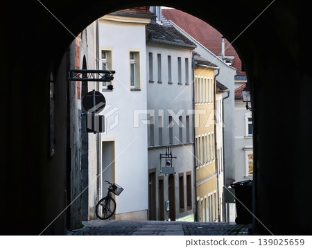 Urban Bike Scene. Narrow Street With Bicycle. Shadowed Alleyway Featuring Leaning Bicycle And Stone Stairs Urban Bike Scene. Narrow Street With Bicycle. Shadowed Alleyway Featuring Leaning Bicycle And Stone Stairs 139025659