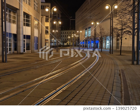 Tranquil Nighttime City Scene Featuring Empty Railway Tracks And Brightly Illuminated Structures 139025720