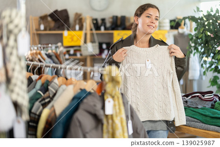 European woman chooses jersey sweater in store European woman chooses jersey sweater in store 139025987