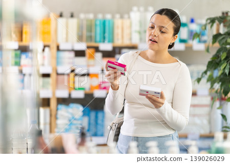 Middle-aged woman customer choosing paracetamol in drugstore Middle-aged woman customer choosing paracetamol in drugstore 139026029