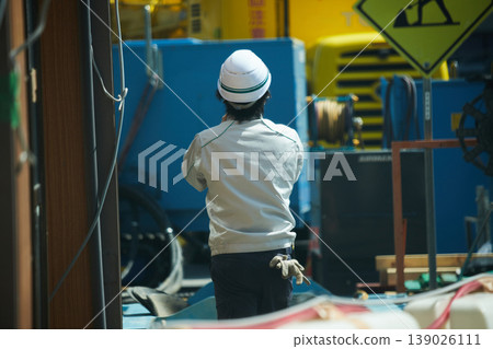 The back view of a male construction worker at a construction site. 139026111