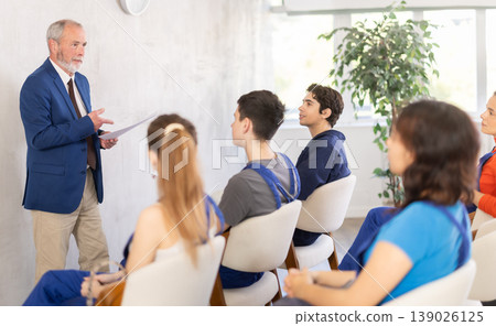 Senior teacher speaking to students in blue overalls Senior teacher speaking to students in blue overalls 139026125