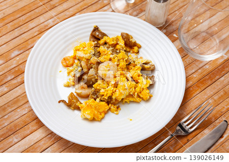 Hearty and healthy meal is fried scrambled eggs with pieces of mushrooms, herbs and shrimp 139026149