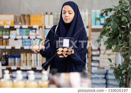 Middle-aged Muslim woman choosing cosmetics in chemist's shop Middle-aged Muslim woman choosing cosmetics in chemist's shop 139026197