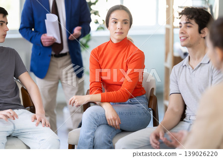 Youth girls and guys sit at circle, senior man coach keep watch over Youth girls and guys sit at circle, senior man coach keep watch over 139026220