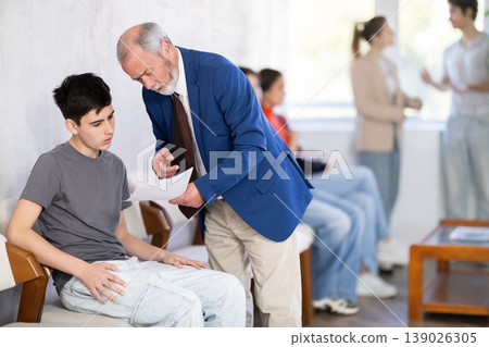 Mature male HR specialist conducts brief interview with guy applicant, queue in background Mature male HR specialist conducts brief interview with guy applicant, queue in background 139026305