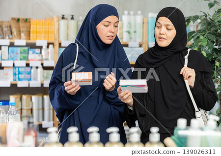 Muslim female customers discussing choice of medicines in drugstore Muslim female customers discussing choice of medicines in drugstore 139026311