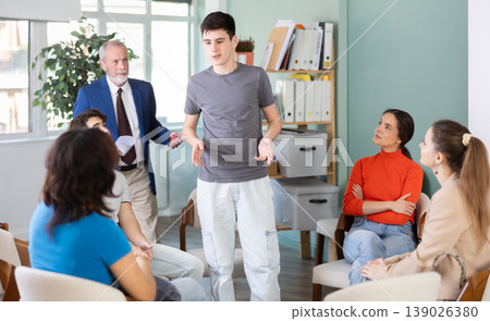 Guy stands in front of other young people in a circle and tells his opinion Guy stands in front of other young people in a circle and tells his opinion 139026380