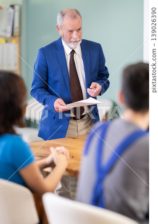 Senior manager speaking to a group of young workers around table Senior manager speaking to a group of young workers around table 139026390