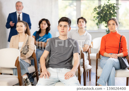 Young students listening to lecture with a teacher standing in background Young students listening to lecture with a teacher standing in background 139026400