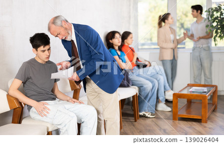 Mature male HR specialist conducts brief interview with guy applicant, queue in background Mature male HR specialist conducts brief interview with guy applicant, queue in background 139026404
