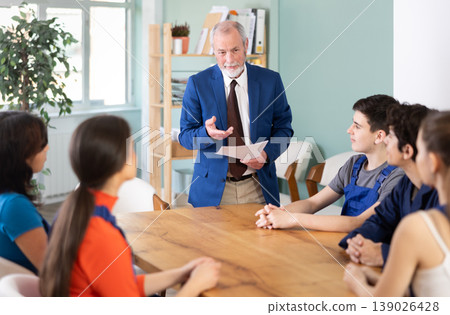 Team of builders and foremen sits at the table and listens to the tasks Team of builders and foremen sits at the table and listens to the tasks 139026428