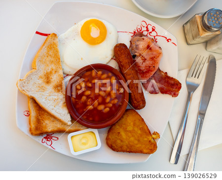 English breakfast with beans, fried egg, bacon, sausage, toasts and hash brown 139026529