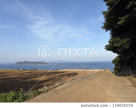 A road leading to the sea and a rural landscape; a blue sky and a calm sea. A road leading to the sea and a rural landscape; a blue sky and a calm sea. 139026559