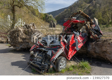 Severely damaged crushed car wreck after accident with debris and fallen tree trunk Severely damaged crushed car wreck after accident with debris and fallen tree trunk 139027370