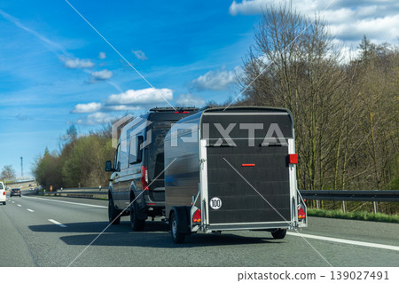 Van towing cargo trailer on highway road transportation logistics and delivery concept Van towing cargo trailer on highway road transportation logistics and delivery concept 139027491