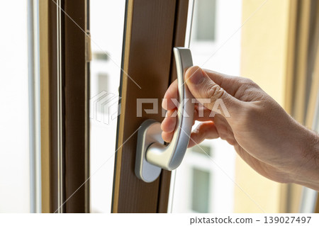 Close up of hand installing window safety lock mechanism for child protection at home Close up of hand installing window safety lock mechanism for child protection at home 139027497
