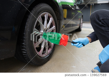 Manual car wheel cleaning with brush and gloves detailing process close up Manual car wheel cleaning with brush and gloves detailing process close up 139027569