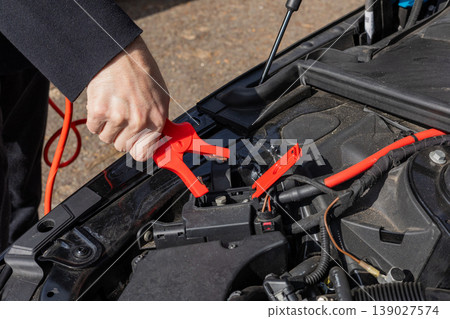 Jump starting car battery with cables emergency roadside assistance automotive concept 139027574