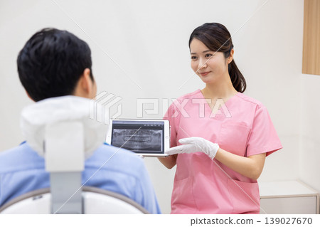 Dentist explaining while showing a tablet Dentist explaining while showing a tablet 139027670