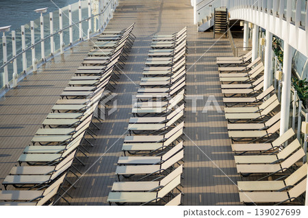 Empty Cruise Ship Sun Deck with Neatly Arranged Lounge Chairs by the Sea 139027699