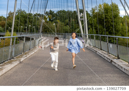Boy and girl running freely across a pedestrian bridge. Boy and girl running freely across a pedestrian bridge. 139027709