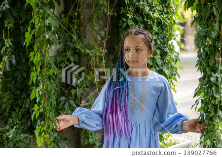 A natural portrait of a young woman standing amid lush greenery. A natural portrait of a young woman standing amid lush greenery. 139027766