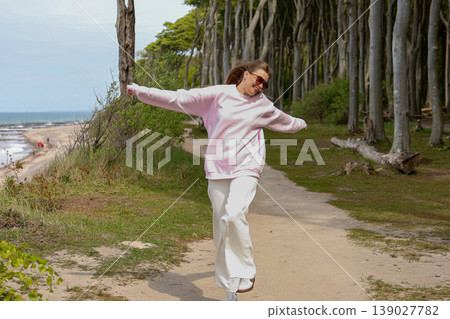 Happy Young Woman Walking On Coastal Trail With Arms Open Near Sea 139027782