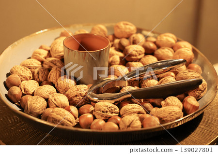 Decorative bowl filled with walnut and hazelnut placed on a stylish table. Decorative bowl filled with walnut and hazelnut placed on a stylish table. 139027801