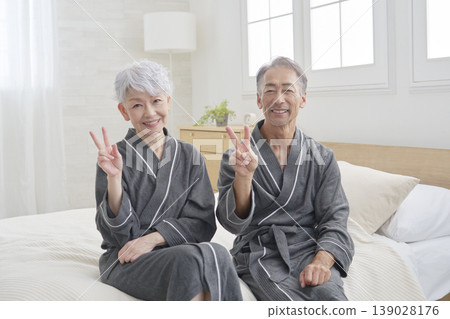 Senior couple making peace signs in their bedroom Senior couple making peace signs in their bedroom 139028176
