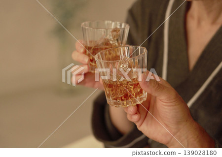 Senior couple drinking whiskey in the bedroom, no faces Senior couple drinking whiskey in the bedroom, no faces 139028180