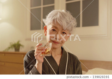 Senior woman drinking whiskey in bedroom Senior woman drinking whiskey in bedroom 139028191