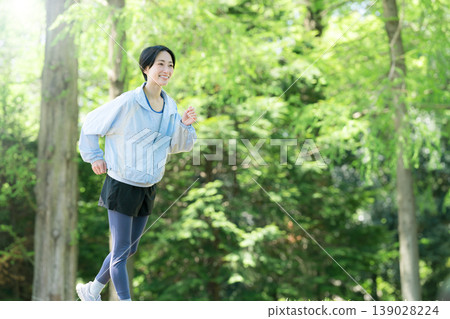 In a refreshing outdoor park surrounded by lush greenery, women can enjoy aerobic exercise and running, promoting a healthy lifestyle. In a refreshing outdoor park surrounded by lush greenery, women can enjoy aerobic exercise and running, promoting a healthy lifestyle. 139028224