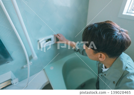 承包商將浴室遙控器更換為環保熱水器。 139028465