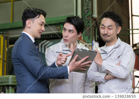 一名工廠工人和一名商人使用平板電腦開會；引入了數位轉型、資訊科技和人工智慧驅動的機械。 139028650
