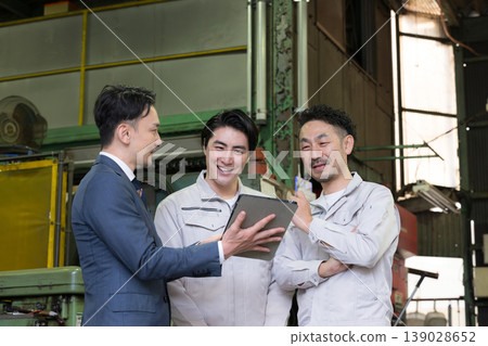 一名工廠工人和一名商人使用平板電腦開會；引入了數位轉型、資訊科技和人工智慧驅動的機械。 139028652