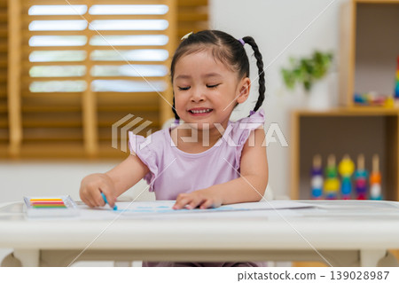 happy preschool child girl drawing and painting with colorful oil pastels on paper 139028987