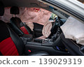 Deployed airbags inside modern car interior with black and red seats 139029319