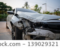 Close-up of damaged white car after front collision with visible dents and broken parts 139029321